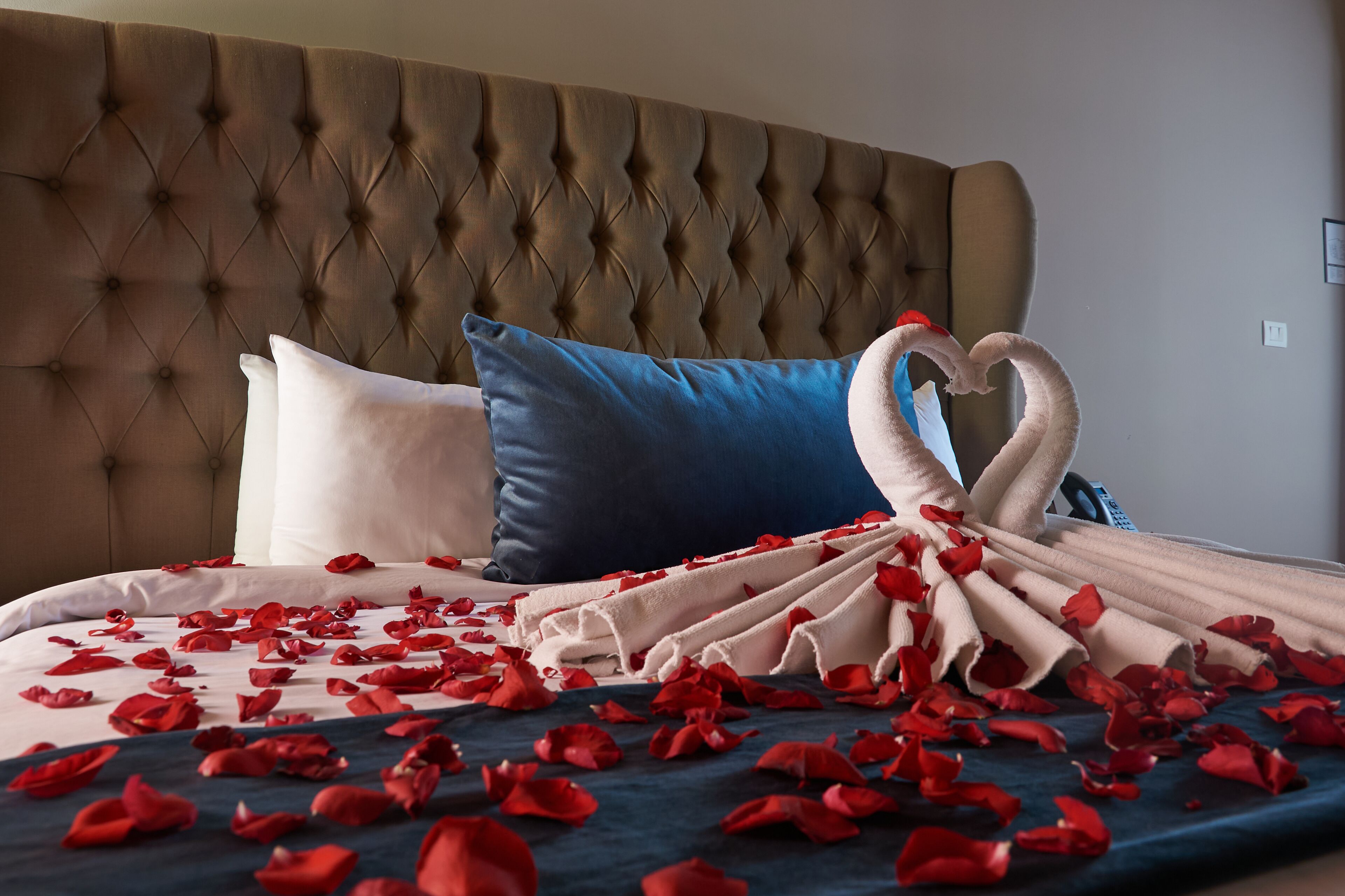 A bed with a tufted headboard, a blue pillow, and a white pillow.