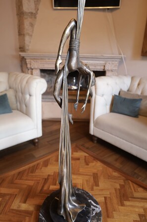 A sculpture on a pedestal in a living room with a fireplace and two white sofas. - Hotel Morelia Boutique Villa Italia (Morelia)