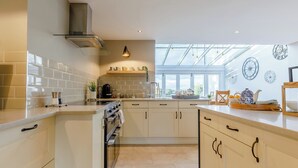 Een moderne keuken met witte kastjes, een inbouwoven en een groot raam dat natuurlijk licht binnenlaat.
