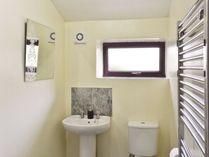 A bathroom with a white sink, a toilet, a window, and a mirror. - Close to the village centre with many walks and cycle routes from the doorstep. (Bradwell)