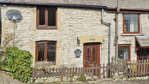A stone cottage with a wooden door, a satellite dish, and a small garden. - Close to the village centre with many walks and cycle routes from the doorstep. (Bradwell)