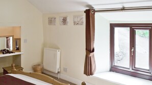 A bedroom with a bed, a radiator, a window with curtains, and a shelf with items. - Close to the village centre with many walks and cycle routes from the doorstep. (Bradwell)