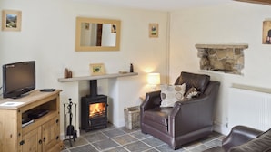 A living room with a fireplace, a television, and a leather sofa. - Close to the village centre with many walks and cycle routes from the doorstep. (Bradwell)