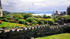 A coastal town with stone walls, a signboard, and a view of the sea. - Criccieth holiday apartment is a bolthole for two in a converted church. (Criccieth, near Llyn Peninsula)