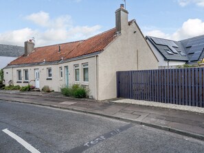 A two-story house with a red-tiled roof, a white door, and a blue fence.