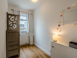 A small, well-lit room with a window, radiator, and a cabinet with a mirror.