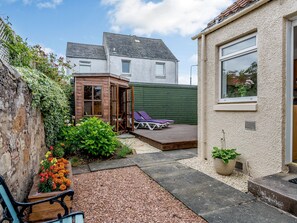 A small backyard with a wooden deck, a seating area, and a garden with marigolds.