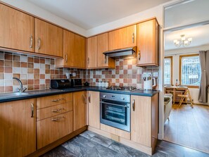 Une cuisine moderne avec des meubles en bois, une cuisinière à gaz et un four encastré.