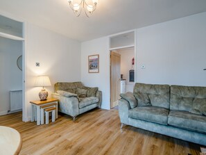 A living room with two grey sofas, a wooden coffee table, a lamp, and a framed picture on the wall.