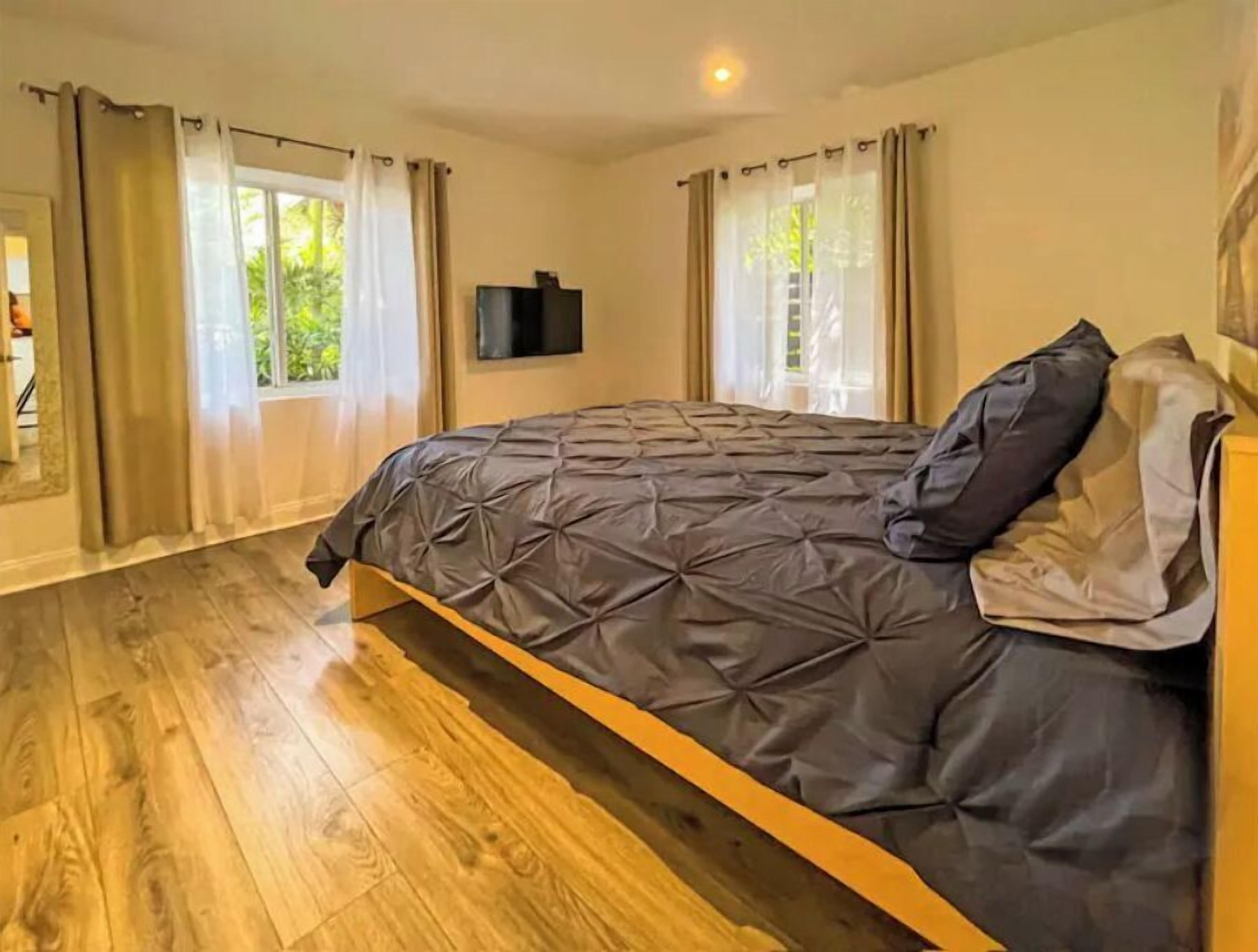 A bedroom with a bed, wooden flooring, and curtains.