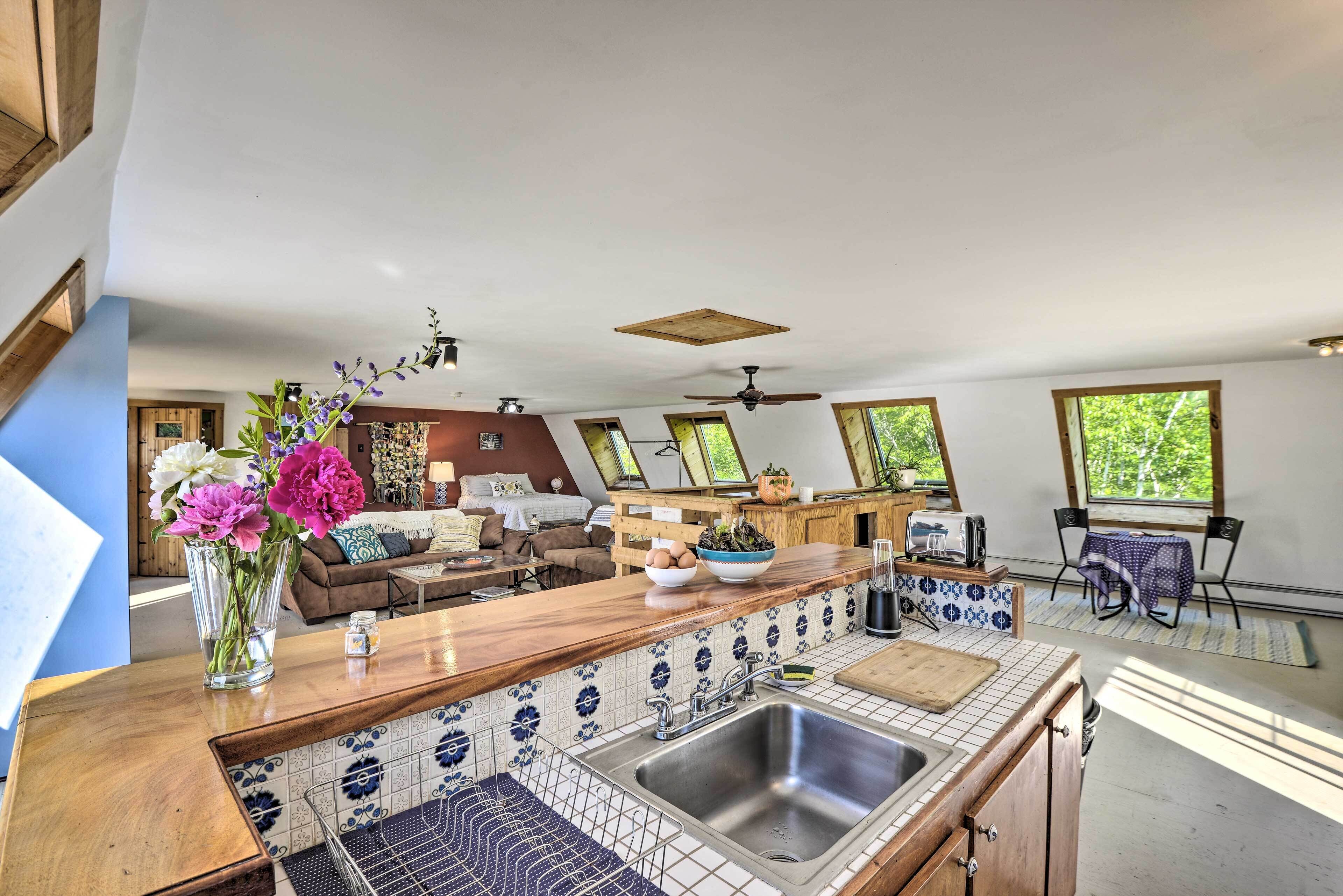 Una cocina moderna con una isla central, un comedor con mesa y sillas, y una sala de estar con sofá y mesa de centro.