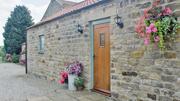 A stone building with a wooden door, a window, and flower boxes.