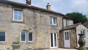 A stone building with multiple windows and a door, featuring a stone pathway and a large planter. - 2 bedroom accommodation in Youlgreave near Bakewell (Youlgreave near Bakewell)