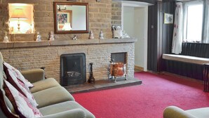 A cozy living room with a stone fireplace, comfortable seating, and a red carpet. - 2 bedroom accommodation in Youlgreave near Bakewell (Youlgreave near Bakewell)