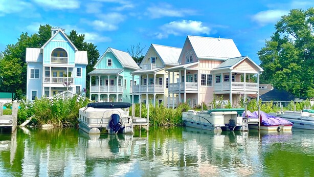 Una hilera de casas coloridas junto a un lago tranquilo, con barcos amarrados en la orilla.