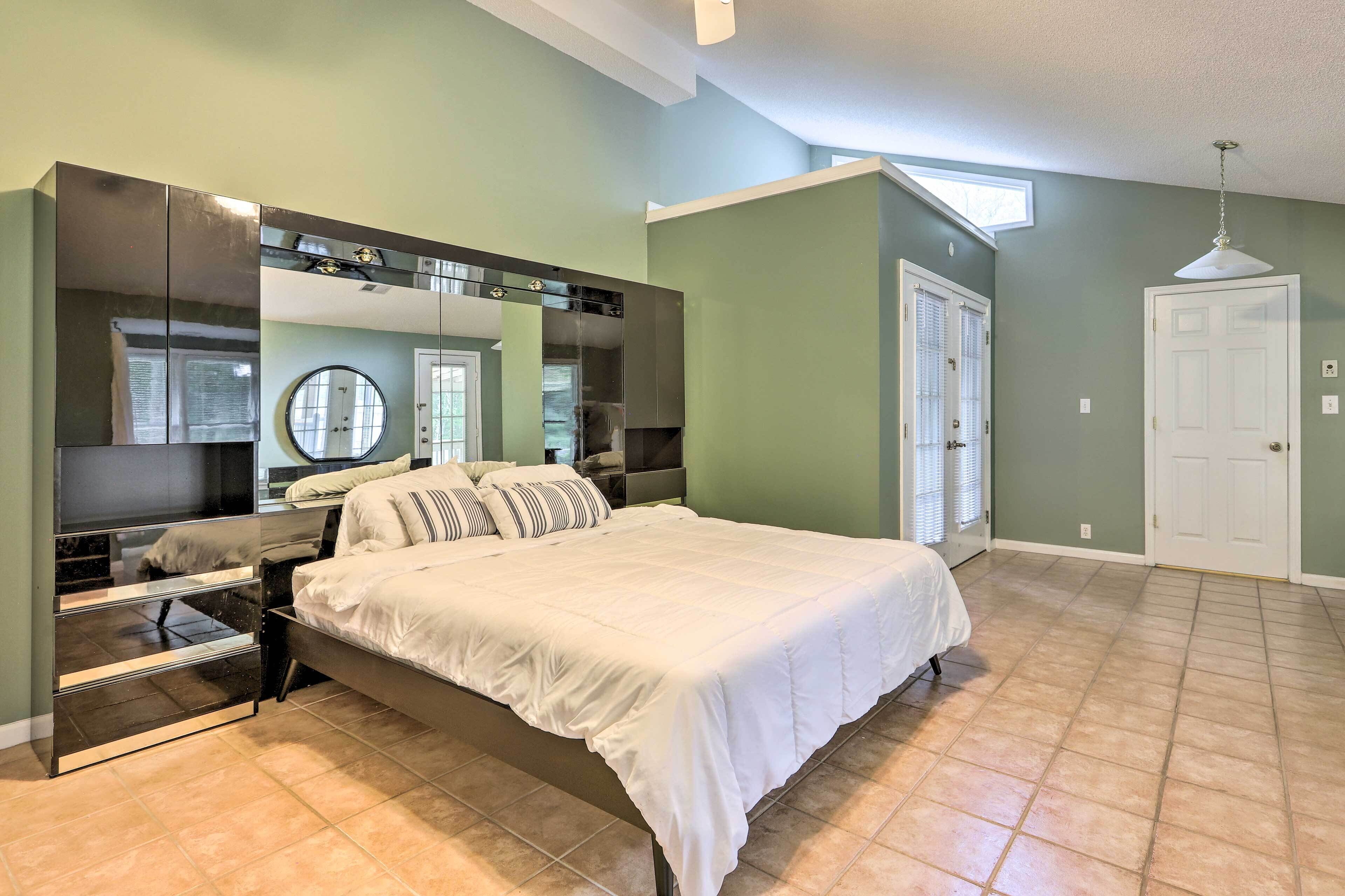 Une chambre à coucher avec un grand lit, une armoire intégrée, un miroir et une porte.