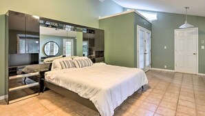 Een slaapkamer met een groot bed, een inbouwkast, een spiegel en een deur.