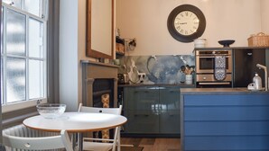 Uma cozinha moderna com área de jantar, apresentando uma mesa redonda, cadeiras, forno embutido e um relógio na parede.
