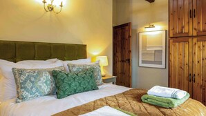 A neatly made bed with a quilted headboard, two pillows, and folded towels on a brown bedspread.