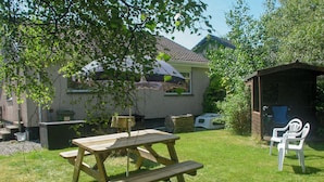 A wooden picnic table with benches in a grassy backyard with a house in the background. - 2 bedroom accommodation in Portree, Isle of Skye (Portree, Isle of Skye)