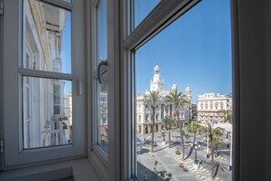 A view from a window of a building with a large open plaza, palm trees, and a prominent white building with a dome in the background. - Scheherazade apartment and the city of Cadiz (Cádiz)