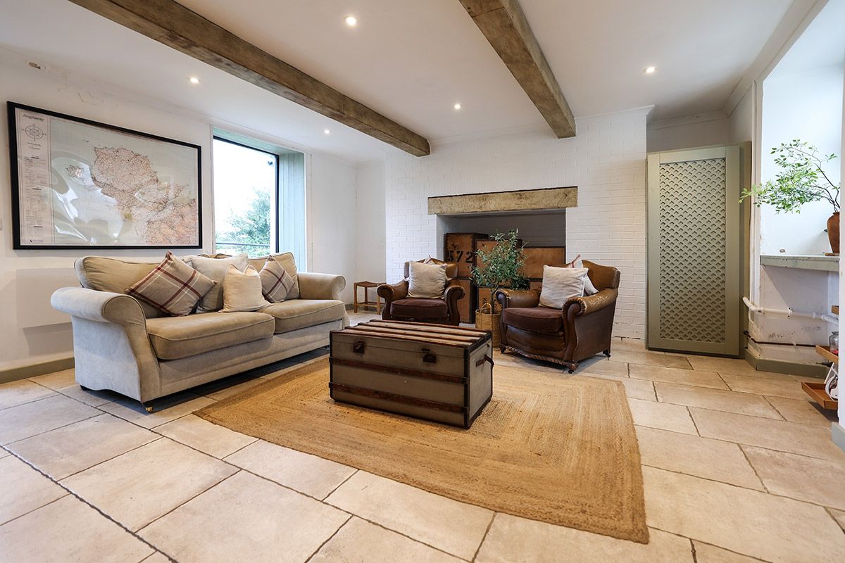 A living room with a sofa, armchairs, a wooden chest, and a fireplace.