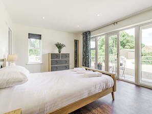 Un dormitorio con una cama grande, un aparador, un ventanal y vistas al exterior.