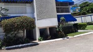 A multi-story building with balconies, a central column, and a blue awning. - Cozy vacation apartment in Kingston (Kingston)