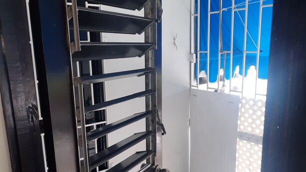 A room with a metal gate, white tiled floor, and a blue window. - Cozy vacation apartment in Kingston (Kingston)