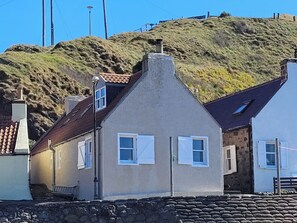 Um edifício costeiro com base de pedra, telhado inclinado e chaminé.