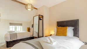 Een hotelkamer met twee bedden, een grote spiegel, een hanglamp en een raam met uitzicht.