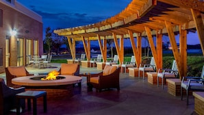 Eine Außenpatio mit Feuerstelle, Sitzgelegenheiten und einer Holz-Pergola.
