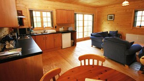 L'intérieur d'un chalet en bois comprend une cuisine, un coin repas et un salon.