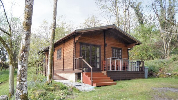 Un chalet en bois doté d’un porche et d’un escalier menant à l’entrée.