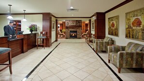 A hotel lobby with a reception desk, seating area, fireplace, and artwork on the walls. - Fully-Equipped Suite |Pool + Wi-Fi (Elkhart)