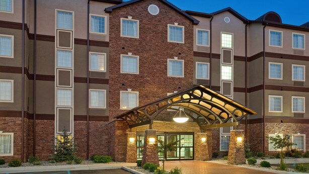 A multi-story hotel with a brick facade, large windows, and a covered entrance area. - Fully-Equipped Suite |Pool + Wi-Fi (Elkhart)