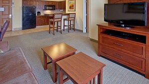 A compact living space with a kitchenette, a flat-screen TV, a dining area with a table and chairs, and a sofa. - Fully-Equipped Suite |Pool + Wi-Fi (Elkhart)