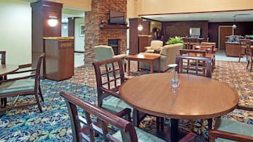 Un hall d’hôtel doté d’une cheminée centrale, d’un espace salon et d’un bar.