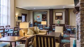 A hotel lobby with a seating area, a reception desk, and a fireplace.