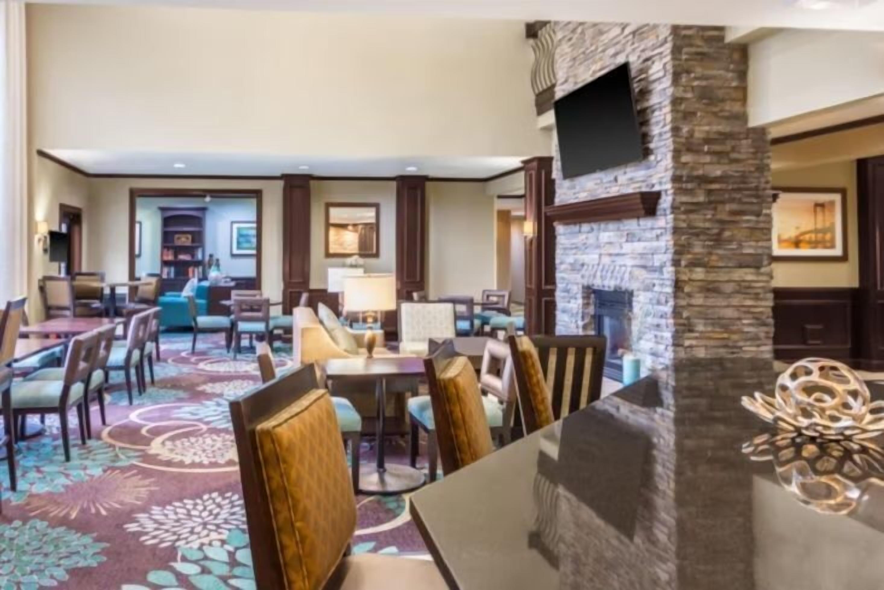 A hotel lobby with a fireplace, seating area, and a television mounted on the wall.