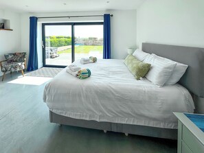 A modern hotel room with a large bed, a view of the outdoors, and a small seating area. - 6 bedroom accommodation in Elmer (Elmer)