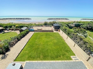 Un jardin avec une pelouse, une piscine et une vue sur la plage.