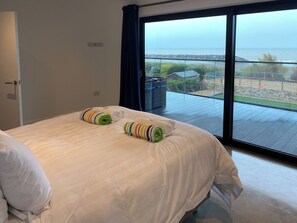 A bedroom with a large window, a bed with white linens, and two rolled towels. - 6 bedroom accommodation in Elmer (Elmer)