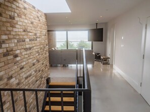 Un intérieur moderne avec un mur en briques, un escalier, un canapé et un téléviseur à écran plat.