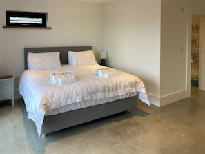 Une chambre d’hôtel moderne dotée d’un grand lit, de linge de lit blanc, d’un téléviseur à écran plat et d’une table de chevet avec une lampe.