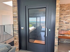 A modern door with a glass panel, a metal handle, and a warning label. - 6 bedroom accommodation in Elmer (Elmer)