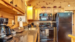 A kitchen with wooden cabinets, a stove, a microwave, and a refrigerator.