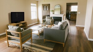 Un salon comprenant une télévision, un canapé, des fauteuils, une table basse et une cheminée.