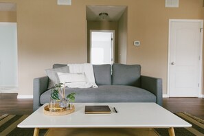 A living room with a grey sofa, a white coffee table, and a small plant on the table.