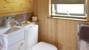 A compact bathroom with a toilet, sink, and window. - Peace and quiet, sat in the middle of your own field with a private hot tub. (Leadburn, near West Linton)